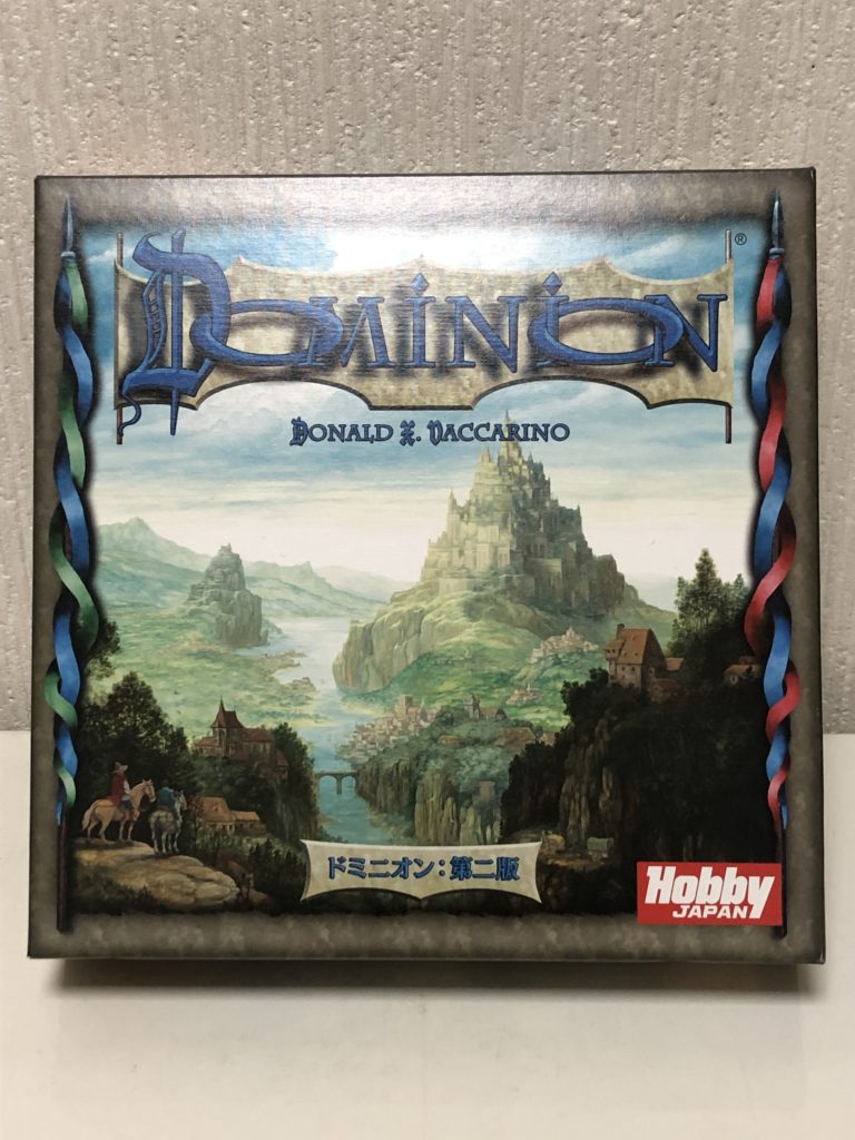 ボードゲーム『ドミニオン第二版』の箱画像。山間にそびえる壮大なお城と風景のイラスト